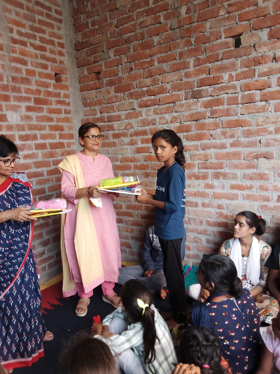 A girl receiving learning materials during a V Learning Trust session